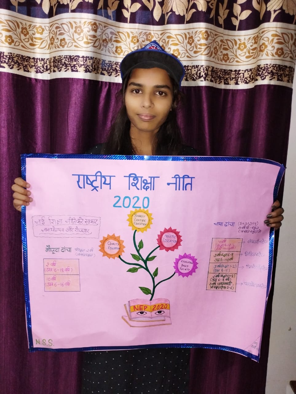 NSS की धौलाधार परिसर ईकाई की ओर से राष्ट्रीय शिक्षा नीति-2020 के क्रियान्वन संबंधी तैयार पोस्टर  के साथ छात्रा।